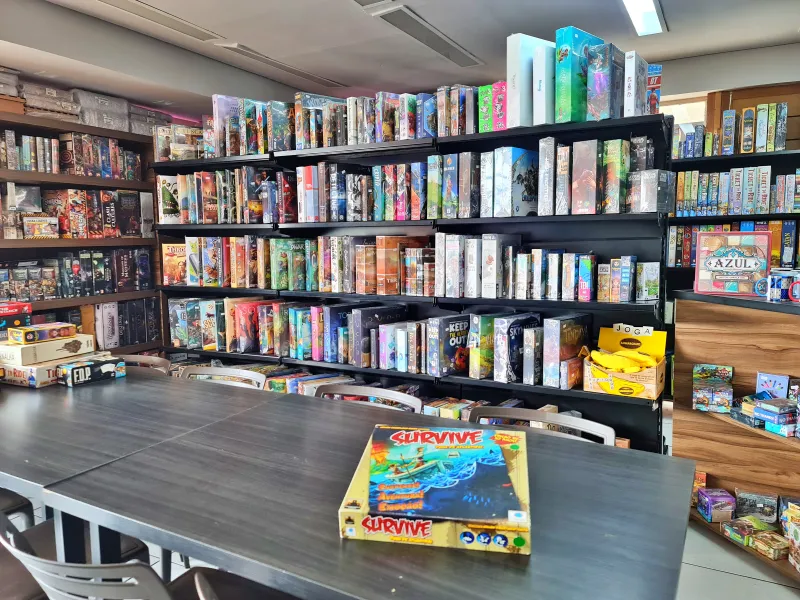 Espaço da Paladins Games em Goiânia com o jogo de tabuleiro Survive em destaque na mesa