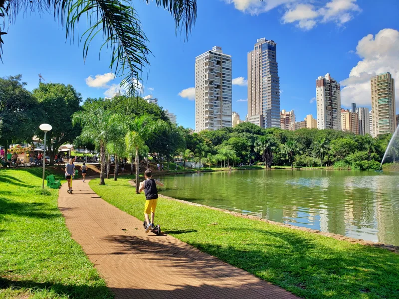 Criança andando de patinete no Parque Vaca Brava em Goiânia em um dia de sol, um dos melhores passeios para fazer com crianças na cidade