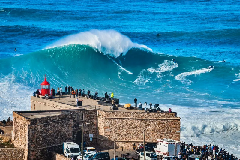 Turistas observando as ondas gigantes de Nazaré, um dos ícones do turismo em Portugal.