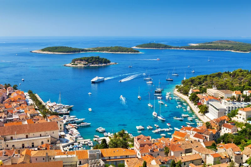 Praia com águas cristalinas e barcos ancorados em Hvar, na Croácia, durante o verão na Europa