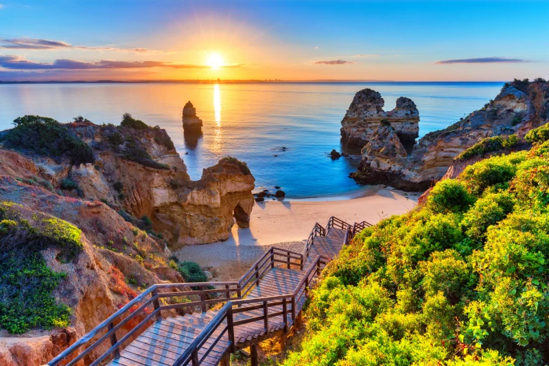 Praia com escadaria e formações rochosas em Lagos, Algarve, em um dia ensolarado
