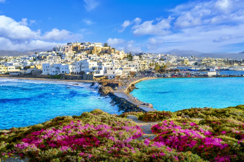Praia em Naxos, na Grécia, com águas cristalinas e montanhas ao fundo — destino ideal para quem busca onde ir na Europa no verão