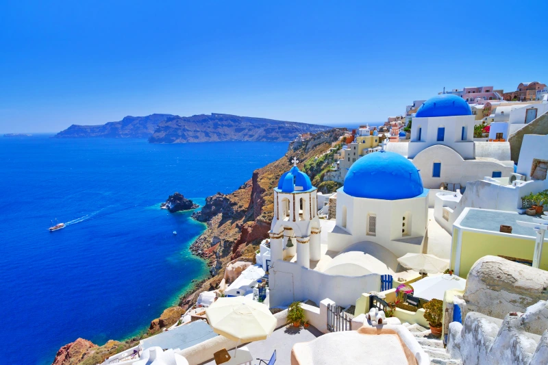 Vista das casas brancas de Santorini com o mar azul ao fundo no verão europeu