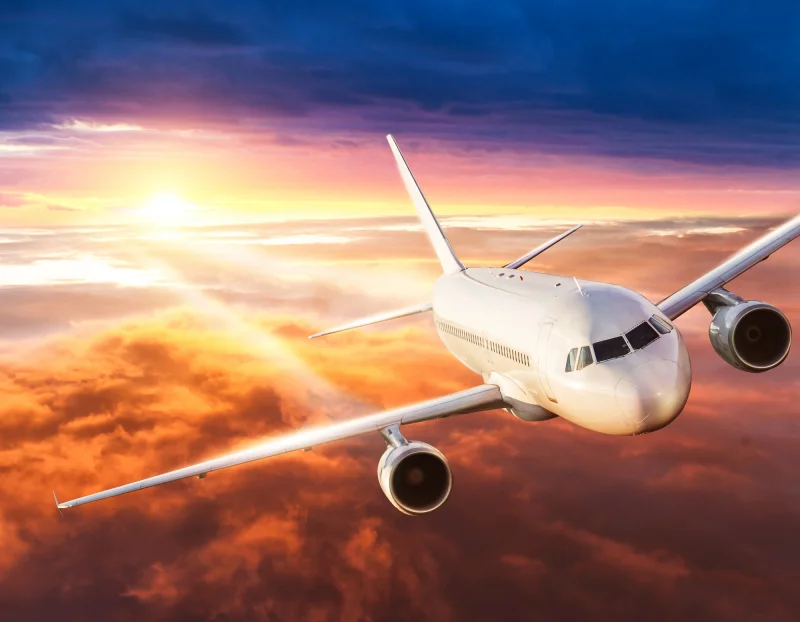 Avião comercial em pleno voo, cruzando um céu limpo, simbolizando o início de uma viagem internacional.