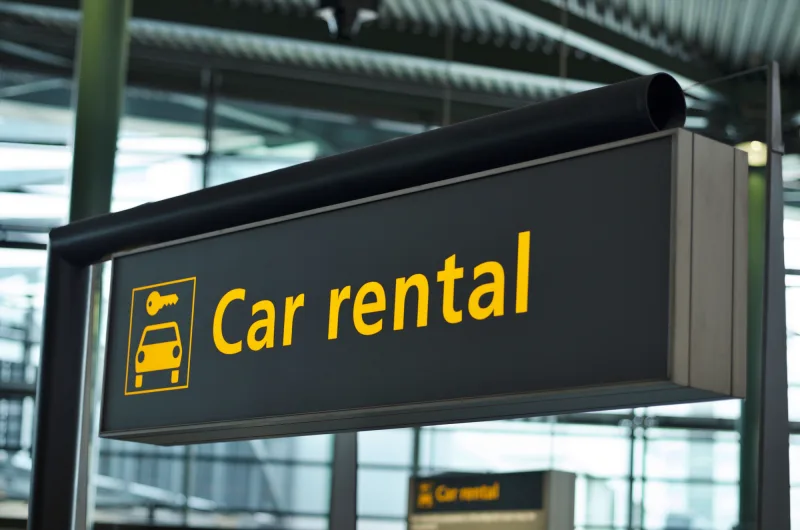 Placa de aluguel de carros em aeroporto, uma comparação dos custos de viajar de carro próprio e alugar um veículo