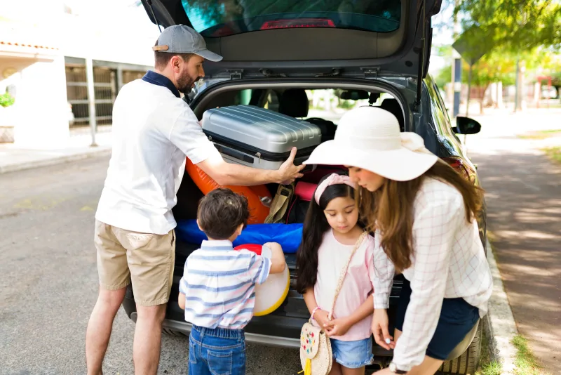 Família colocando malas no carro para uma viagem, preocupados em saber Quanto custa uma viagem de carro