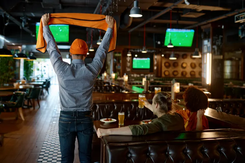 Amigos assistindo jogos de futebol durante uma viagem em um bar