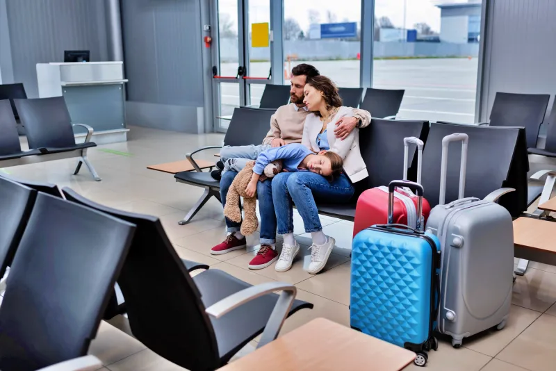 Um casal e sua filha esperando num aeroporto por causa de voo atrasado